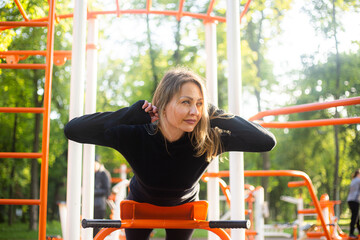 Fototapeta premium The girl on the summer sports ground does sports exercises for the back