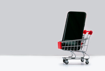 Mobile phone in a supermarket trolley. buying and selling a smartphone. Online store. Consumer credit. isolated white background, concept buying smart phone. Sale business concept. 