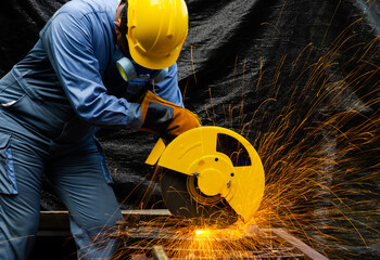 Worker cuts metal by electric circular saw. Fountain of grinding metal sparks. Metal working with...