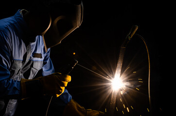Worker welding metal steel with flux shielded arc welding. Welder with personnel protective...