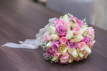 Brides bouquet with ribbon made from roses laying on the wooden table