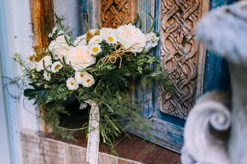 Perspective view of white wedding bouquet standing at the rustic wooden door