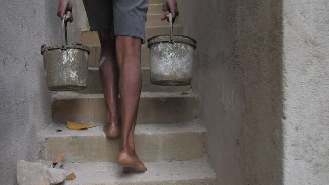 local guy gathers grey wet cement into basket on construction territory slow motion close view. Concept slavery and poverty