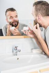 Man applying moisturizer cream in bathroom