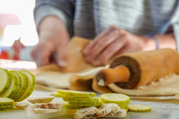A woman rolls dough to make  home-made pizza
