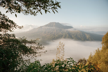 Beautiful landscape volcano mountain Batur in clouds as popular travel destination on Bali at sunrise  in Indonesia in the fog