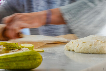 A woman rolls dough to make  home-made pizza