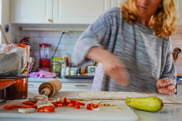A woman rolls dough to make  home-made pizza