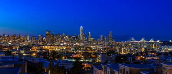 Fototapeta na wymiar San Francisco skyline night panorama with city lights, the Bay Bridge and light trails on the highway