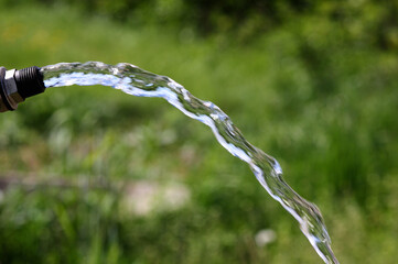 water pouring from a tap on a blurred natural background