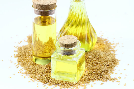 3 Bottles Of Flaxseed Oil And Flax Seeds On A White Background.