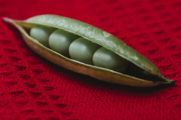 Close-up of fresh green peas isolated on red cloth