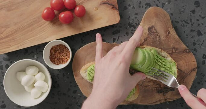 Top View Man Hands Mash Ripe Avocado On Ciabatta Slice For Making Sandwich On Concrete Countertop