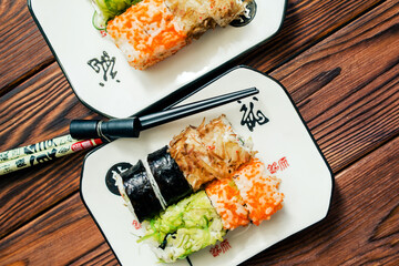Several sushi on a white plate standing on a brown wooden background