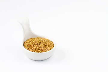 Flax seeds are in a white bowl on a white background and there is space for creativity.