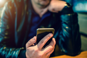 A man writes in her smartphone while sitting in a cafe
