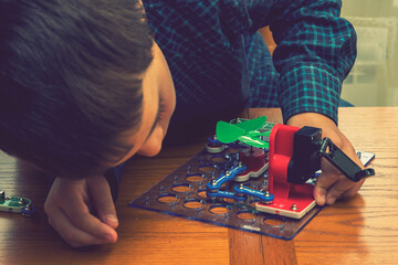 The boy playing an electric constructor. The child is played by intellectual toys. A boy in a blue shirt masters electronics. The concept of early development of children. toned