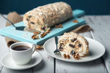 A cup of coffee and meringue roll on a white vintage wooden kitchen table with burlap napkin.