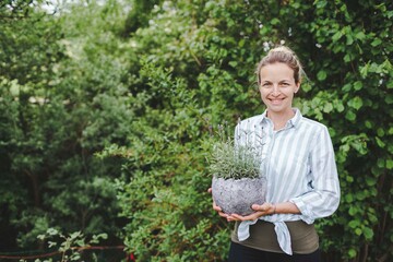 pretty young woman is posing with big and fresh lavender in the garden