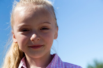Portrait of a cute little girl on the blue sky.