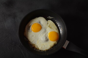 Two fried eggs in cast iron frying pan Healthy easy breakfast on a table. Fresh homemade meal on a frying pan. Traditional breakfast food. International cuisine food. Top view.