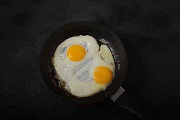 Two fried eggs in cast iron frying pan Healthy easy breakfast on a table. Fresh homemade meal on a frying pan. Traditional breakfast food. International cuisine food. Top view.