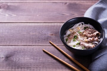 Asian cuisine, Vietnamese pho bo soup in a black plate on a wooden background
