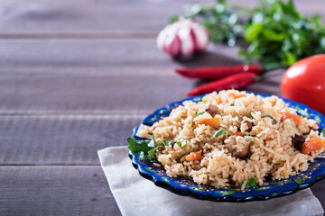 Pilaf - traditional Eastern dish made with rice, vegetables and meat. Asian food. The concept of oriental cuisine , on a wooden table