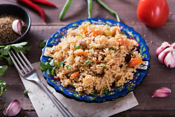 Pilaf - traditional Eastern dish made with rice, vegetables and meat. Asian food. The concept of oriental cuisine , on a wooden table