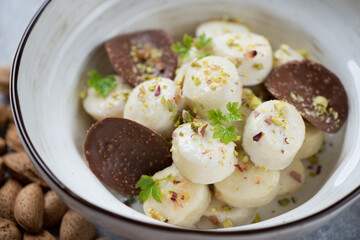 Close-up of curd dumplings or vareniki served in a white bowl with chocolate chips, selective focus