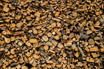 Wall of dry chopped firewood with sunlight, firewood logs in a pile background, firewood wallpaper