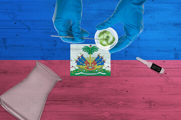 Haiti flag on laboratory table. Medical healthcare technologist holding COVID-19 swab collection...