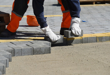 The builder lays concrete tiles on the sand, road works.