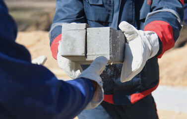 Fototapeta na wymiar Concrete blocks in the hands of builders, close-up.