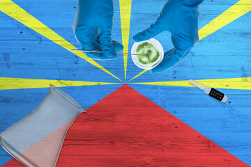 Reunion flag on laboratory table. Medical healthcare technologist holding COVID-19 swab collection...