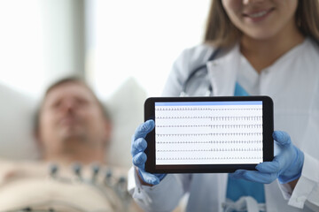 Doctor in clinic shows patients cardiogram tablet