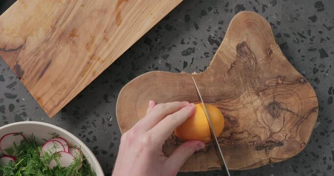 Top view man hands cutting orange lemon on concrete countertop