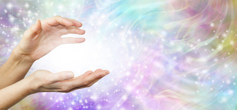 Feeling Healing Energy Between Hands - a pair of female hands with a white energy orb between on an ethereal pink and purple  energy field background 
