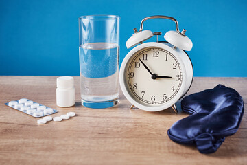 Fototapeta na wymiar Insomnia problem concept. Alarm clock, glass of water and pills on the blue background