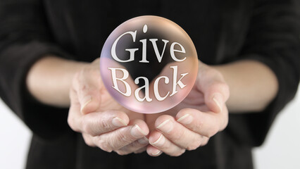 Give Back Campaign Bubble Concept - large transparent rainbow coloured ball showing the words GIVE  BACK inside floating above female cupped hands   
