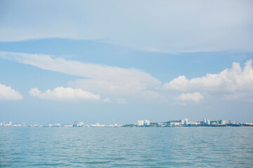 A city far away on the horizon. Sea or ocean shore, buildings and houses, and blue sky with clouds