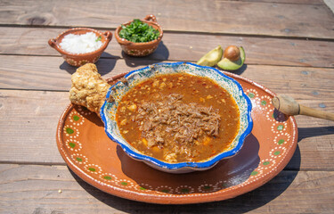 mexican food with birria, hot sauce and chicharron with and avocados, onion and coriander