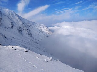 Obraz premium Beautiful view from Himalayan mountain peak with blue sky, white snow and clouds below