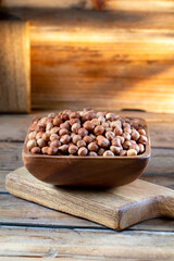 Hazelnuts in brown bowl on rustic wooden background.