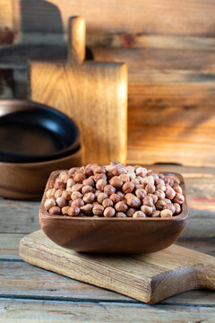 Hazelnuts in brown bowl on rustic wooden background.