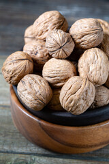 Walnuts in round bowl on wooden rustic background 