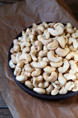 Cashew nuts in round bowl on wooden background 