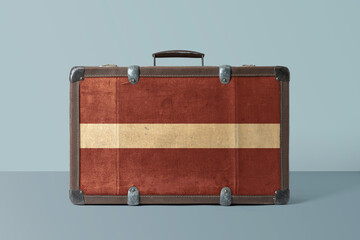 Latvia flag on old vintage leather suitcase with national concept. Retro brown luggage with copy space text.