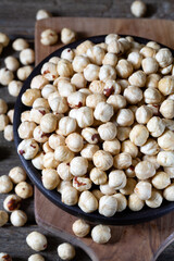 Hazelnuts in brown bowl on rustic wooden background.