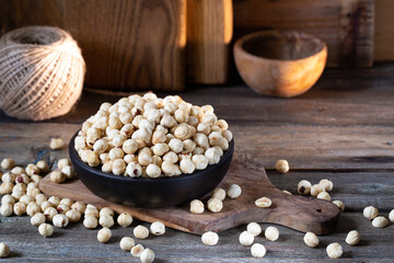 Hazelnuts in brown bowl on rustic wooden background.